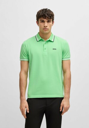 Polo en vert vif avec un col à rayures noires et blanches. Présente un logo sur la poitrine et des manches courtes, fabriqué dans un tissu lisse et respirant.