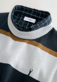 Navy blue knit sweater with white and mustard stripes, featuring a ribbed collar and a checkered fabric interior. Small logo near the bottom.