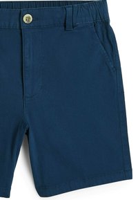 Tmavomodré šortky vyrobené z látky s hladkou textúrou. Majú elastický pás, zapínanie na gombík a bočné vrecká.