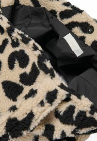 Jakna od flisa s leopard uzorkom i crnim tiskom na bež pozadini, sa glatkom crnom podstavom i etiketom sa natpisom "ONLY."