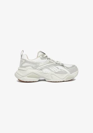 Scarpa da ginnastica atletica in mesh bianca e grigia con suola spessa, chiusura con lacci e linguetta sul tallone, mostrata in profilo laterale.