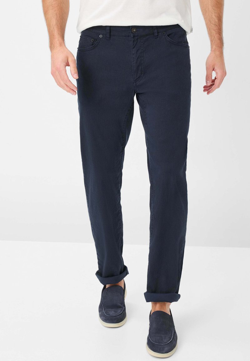 Pantalons en coton bleu marine avec une coupe droite, présentant des poignets retroussés, des poches avant et des détails de couture subtils.