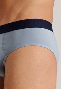 Slip blu chiaro da uomo con cintura navy e logo impresso. Texture liscia e design aderente, che mette in risalto l'apertura della gamba e i dettagli delle cuciture.