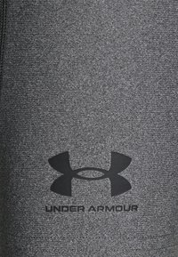 Tissu athlétique gris avec une finition texturée. Comprend un logo Under Armour noir bien en vue et le nom de la marque en dessous.