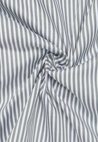 Tessuto di cotone con sottili righe verticali in verde scuro e bianco, che presenta una consistenza liscia e un design finemente tessuto.