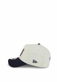 Cap mit einem cremefarbenen Stoffkörper, navyfarbener Schirm, besticktem Logo auf der Vorderseite und kontrastierenden Nähten. Verfügt über eine strukturierte Form und einen verstellbaren Rücken.
