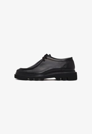 Zwarte leren schoenen met een ronde neus, een laag profiel en een gestructureerd oppervlak. Voorzien van een dikke, robuuste zool met zichtbare profielpatronen.