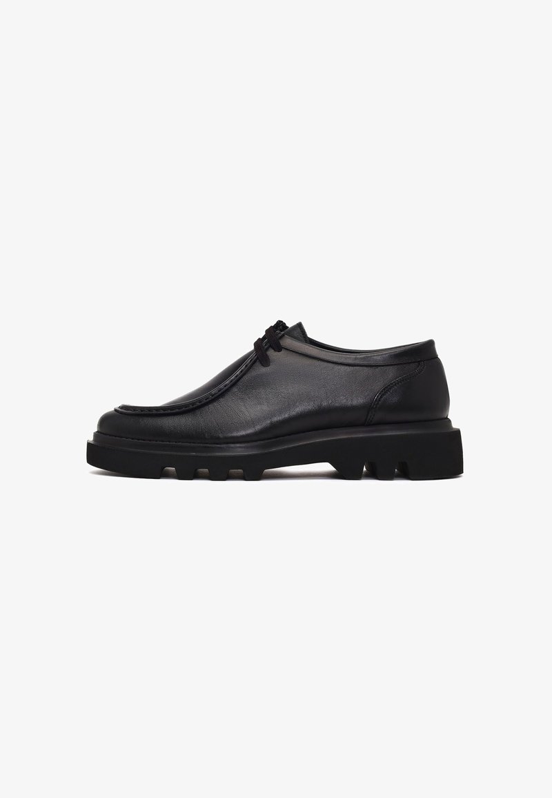 Zwarte leren schoenen met een ronde neus, een laag profiel en een gestructureerd oppervlak. Voorzien van een dikke, robuuste zool met zichtbare profielpatronen.