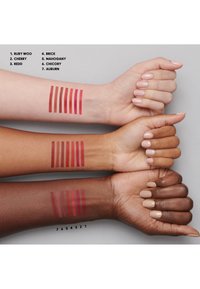 Three arms with swatches of red lip colors: Ruby Woo, Cherry, Redd, Brick, Mahogany, Chicory, Auburn. Different skin tones and textures visible.