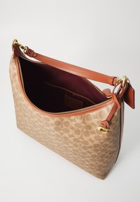 Borsa a tracolla in tessuto beige con un motivo distintivo, dettagli in pelle marrone, tasca interna con zip e zip in tonalità oro.
