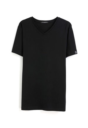 T-shirt noir à manches courtes avec col en V et une petite étiquette logo blanche sur la manche gauche, présenté sur fond blanc.