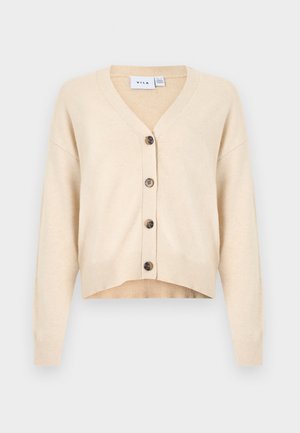 Cardigan beige en tissu tricoté doux, doté d'un col en V, de manches longues et de six boutons marron foncé sur le devant, avec un ourlet court.