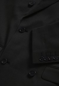 Melnā teksturētā žakete, kurai ir seši matēti pogas, krūšu kabata un izstrādāta šuvšana uz aproces. Audumam ir gluda apdare.