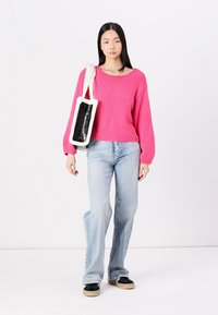 Pink knit sweater with ribbed hem, balloon sleeves; light blue flared jeans; black and white handbag with a furry strap; black shoes.