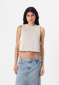 Top en maille côtelée cropped beige clair avec un col rond côtelé et des cordons sur les côtés, associé à une jupe en denim taille haute.