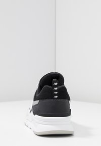 Czarno-biały sportowy sneaker z siateczkową cholewką, wyściełanym kołnierzem i kontrastującą gumową podeszwą. Posiada pętelkę z logo na pięcie.