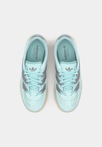 Gai ziliņi zamšā ar pelēkām svītrām, plakani šņorēšana, mīksts apkakles un gumijas zole. Adidas logo uz valkātāja un iekšējās zoles.