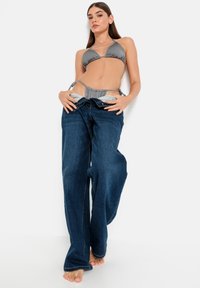 Γκρι μπικίνι τοπ με ρυθμιζόμενες ζώνες, συνδυασμένο με άνετους, σκούρους μπλε τζιν με ίσια γραμμή και ορατή ραφή.