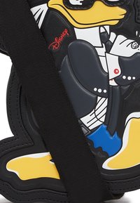 Diseño del personaje Pato Donald sobre un material negro con acentos vibrantes en amarillo, azul y blanco; presenta una correa negra para soporte.