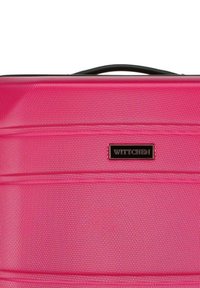 Valise rose avec une surface texturée, dotée de coutures horizontales et d'une poignée supérieure noire. Comprend un logo "Wittchen" en relief doré.