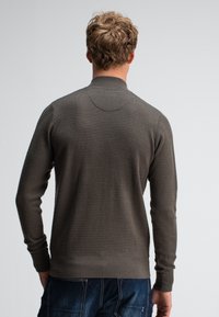 Grijze gebreide trui met een gestructureerd patroon, lange mouwen en een hoge kraag. Heeft rib gebreide manchetten en een zoom voor een getailleerde look.