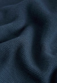 Nahaufnahme von dunkelblauem gestricktem Stoff mit sichtbarer Textur und weichen Falten.