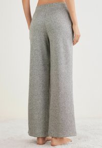 Pantalones de pierna ancha grises, hechos de un tejido suave y texturizado, con una cintura alta y un corte relajado, ideales para un uso casual.