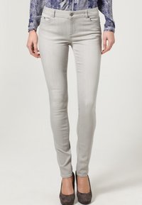 Ljusgråa skinny jeans i denim, med klassisk femficksdesign och subtila blekningar, tillsammans med mörka mockaskor.