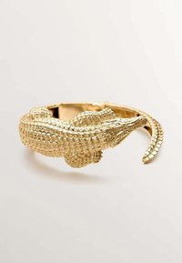 Pulsera de tono dorado con forma de cocodrilo, que presenta escamas detalladas, un acabado texturizado y un diseño abierto con una cabeza y cola prominentes.