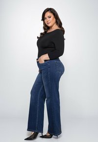 Zwarte langemouwen top gecombineerd met hoge taille, wijde blauwe denim jeans. De jeans hebben een klassiek vijf-pocket ontwerp en zijn recht gesneden.