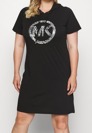 Kvinde iført en sort kortærmet hættetrøjekjole med et cirkulært zebra-print logo på fronten.