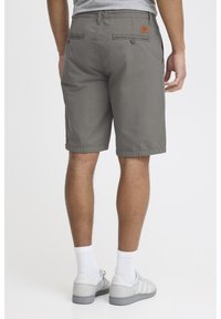 Shorts en coton gris avec deux poches arrière, une fermeture à bouton et un patch en cuir de marque. Ourlet roulé et tissu léger.