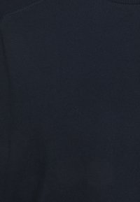 Námořnická modrá bavlněná tkanina s hladkou texturou, s kulatým výstřihem a jemnými švy podél okrajů.