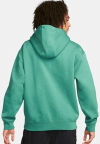 Turkos hoodie med dragsko i huvan, långa ärmar och ribbade muddar. Har en rymlig passform med mjukt, texturerat tyg.