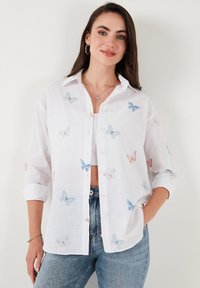 White button-up shirt featuring blue and orange butterfly embroidery, long sleeves rolled at cuffs, made of lightweight fabric.