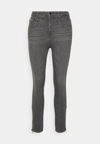 Vaqueros skinny de mezclilla gris con un ajuste slim, detalles con cremallera en los tobillos, diseño de cinco bolsillos y un ligero desgaste en los muslos.
