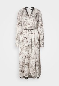 Long sleeved maxi dress in cream fabric with brown artistic cityscape prints. Features a deep V-neck, black waist tie, and cuffed sleeves.