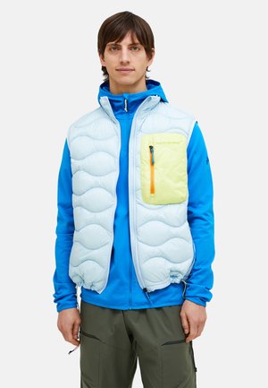 Helleblaue, puffy Weste mit einer gelben Reißverschlusstasche, gerippter Textur und verstellbarem Saum, getragen über einem blauen Langarmoberteil.