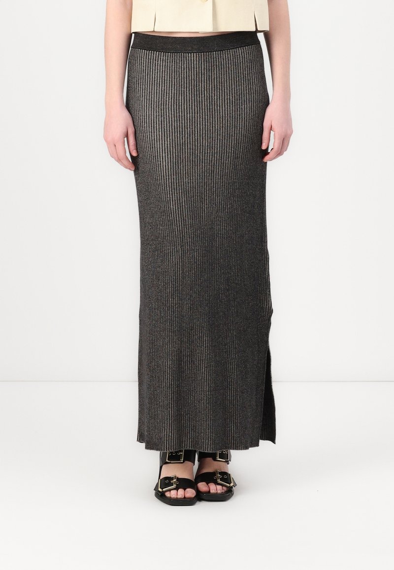 Jupe longue à côtes gris foncé avec une coupe slim et une fente sur le côté. Dotée d'une taille élastique pour plus de confort. Associée à des sandales noires.