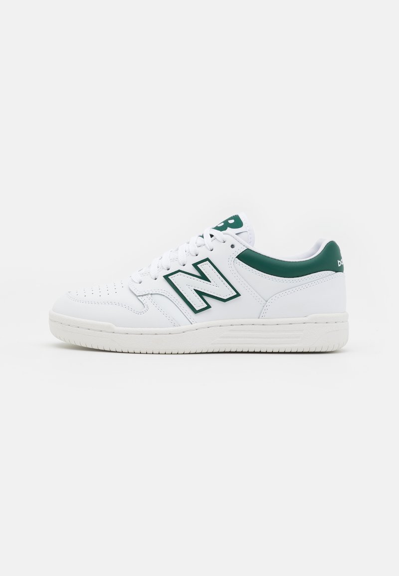 Sapatilha branca com detalhes em verde, parte superior de couro, ponta perfurada, fecho de atacadores e sola de borracha texturizada. Apresenta um destacado logótipo "N".