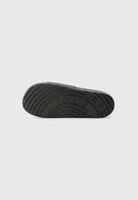 Must musta musta rubberist põhja, millel on tekstuuriga, laineline muster ning selgelt keskel kujutatud "crocs" logo. Lame ja ümar kuju.