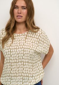 Lett, kortærmet top i beige med et hvidt abstrakt mønster. Rund halsudskæring med en afslappet pasform og glat texture.
