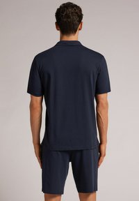 Conjunto de polo y pantalones cortos en color marino, fabricado en tejido suave y ligero. Presenta mangas cortas, un cuello clásico y un ajuste relajado.