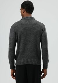 Donkergrijze trui met een geribde kraag, brede manchetten en zoom. Gemaakt van getextureerd gebreid materiaal, met een relaxte pasvorm en een casual ontwerp.