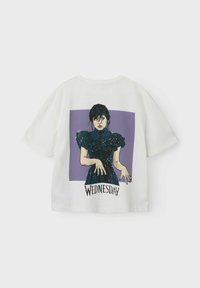 Överdimensionerad vit t-shirt i bomull med en grafik av en karaktär med mörkt hår i en blå klänning på en lila bakgrund, märkt "WEDNESDAY."