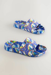 Blå slide-sandaler med ett färgglatt mönster av fotbollar och blanka detaljer, tillverkade av ett glatt syntetiskt material.