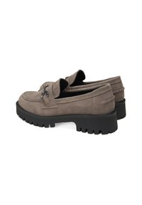 Hellgraue Wildlederloafer mit strukturierter Oberfläche, kontrastierender dickem schwarzen Gummisohle und dekorativen metallischen Akzenten an der Oberseite.