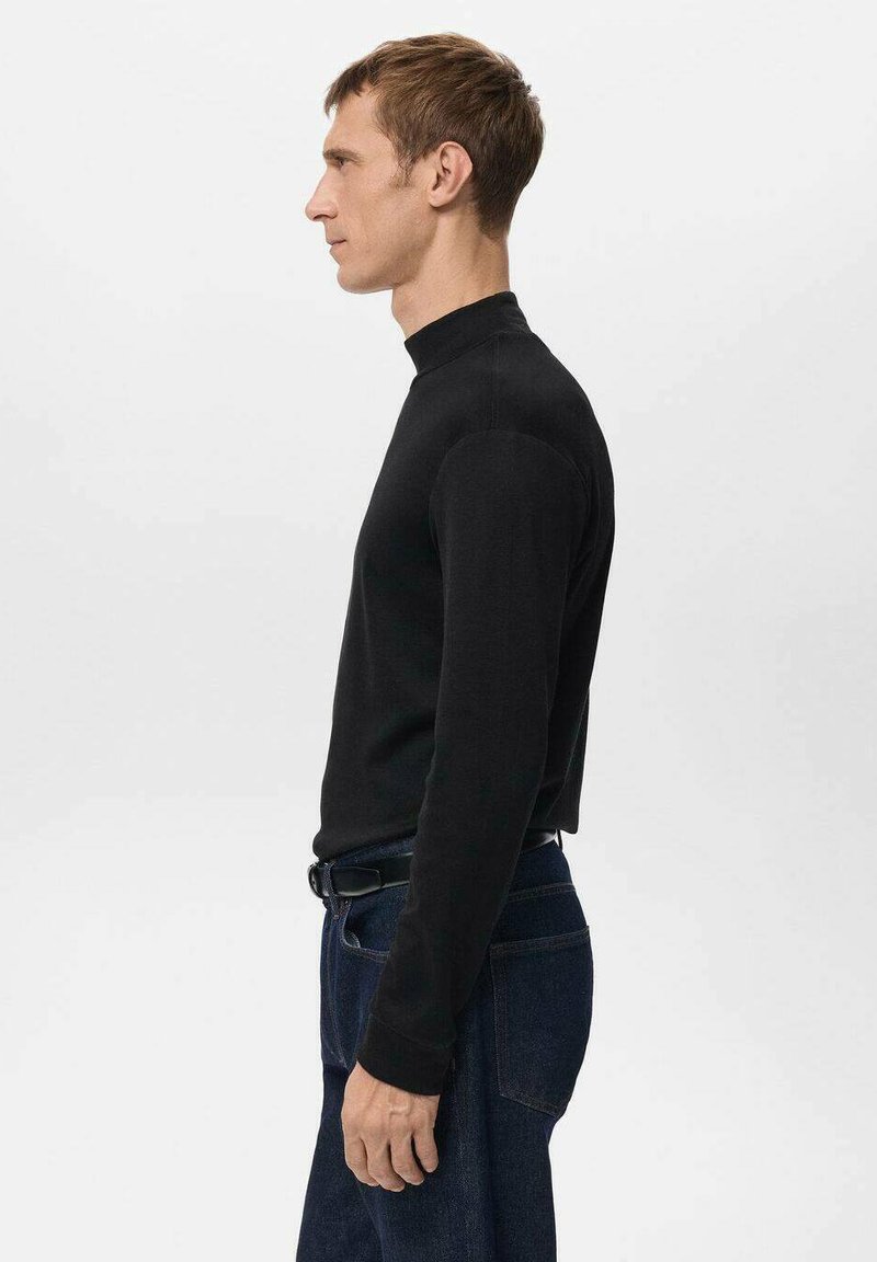 Black turtleneck sweater in a fitted design, featuring long sleeves and a smooth texture, paired with dark denim jeans.