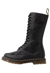 Černá kožená šněrovací bota s květinovou výšivkou, kulatou špičkou a silnou, průhlednou podrážkou s kontrastním žlutým švem.