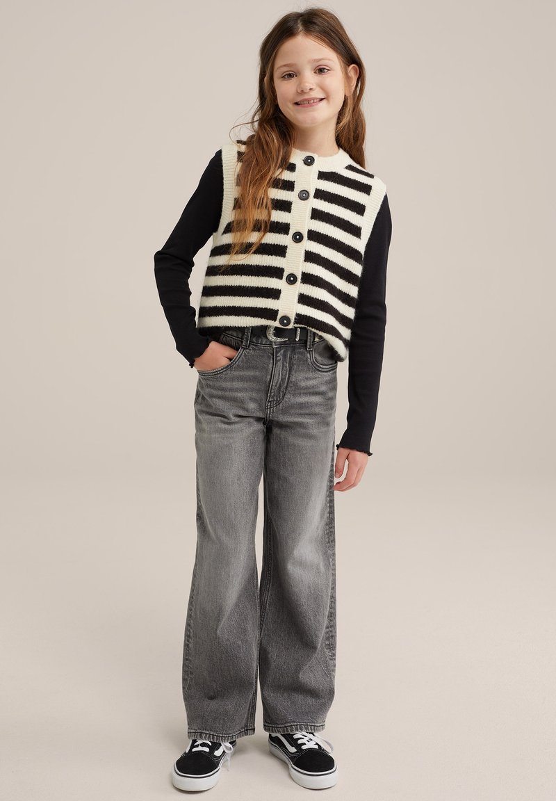 Črno-bela prugasta pletena jopica z gumbi, v kombinaciji z visokim pasom sivimi širokimi hlačami in črnimi supergami.